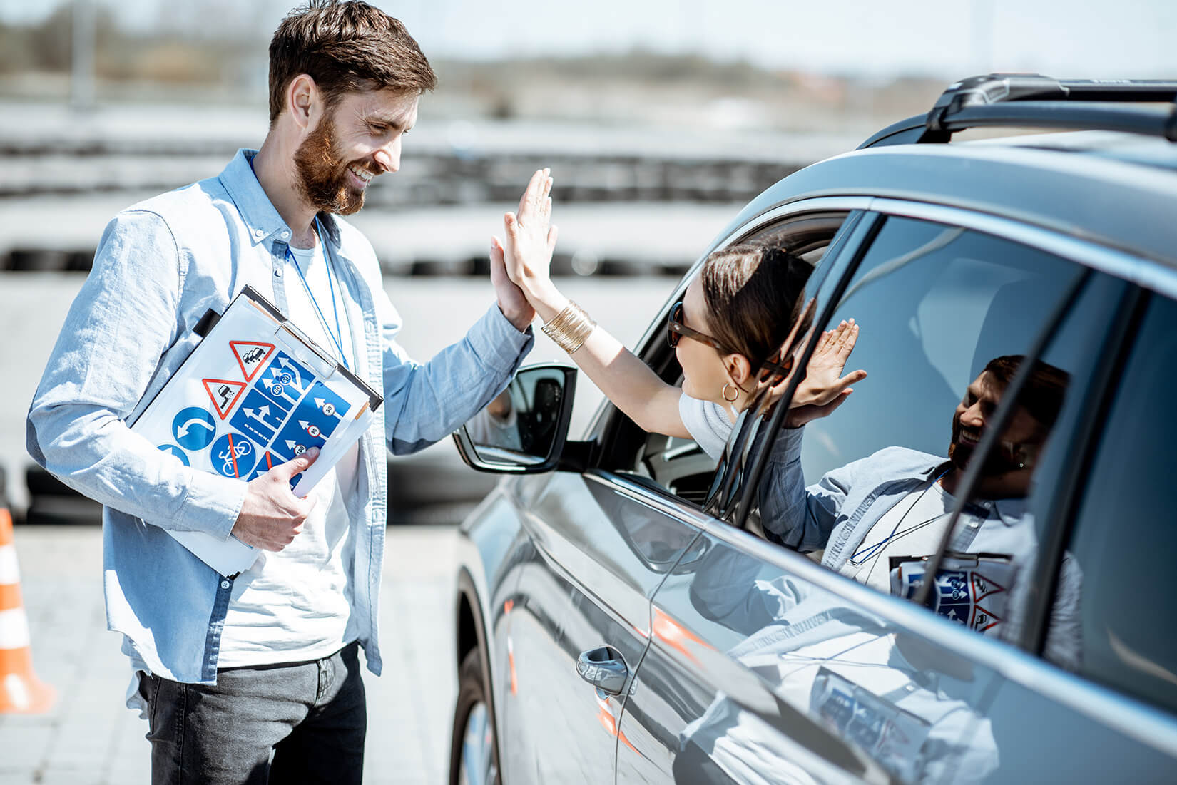 two people high fiving - one inside the car